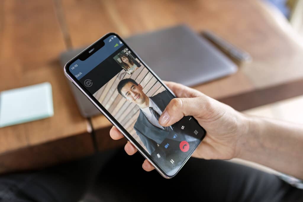 Two people on a live video call using a mobile business app on a smartphone.